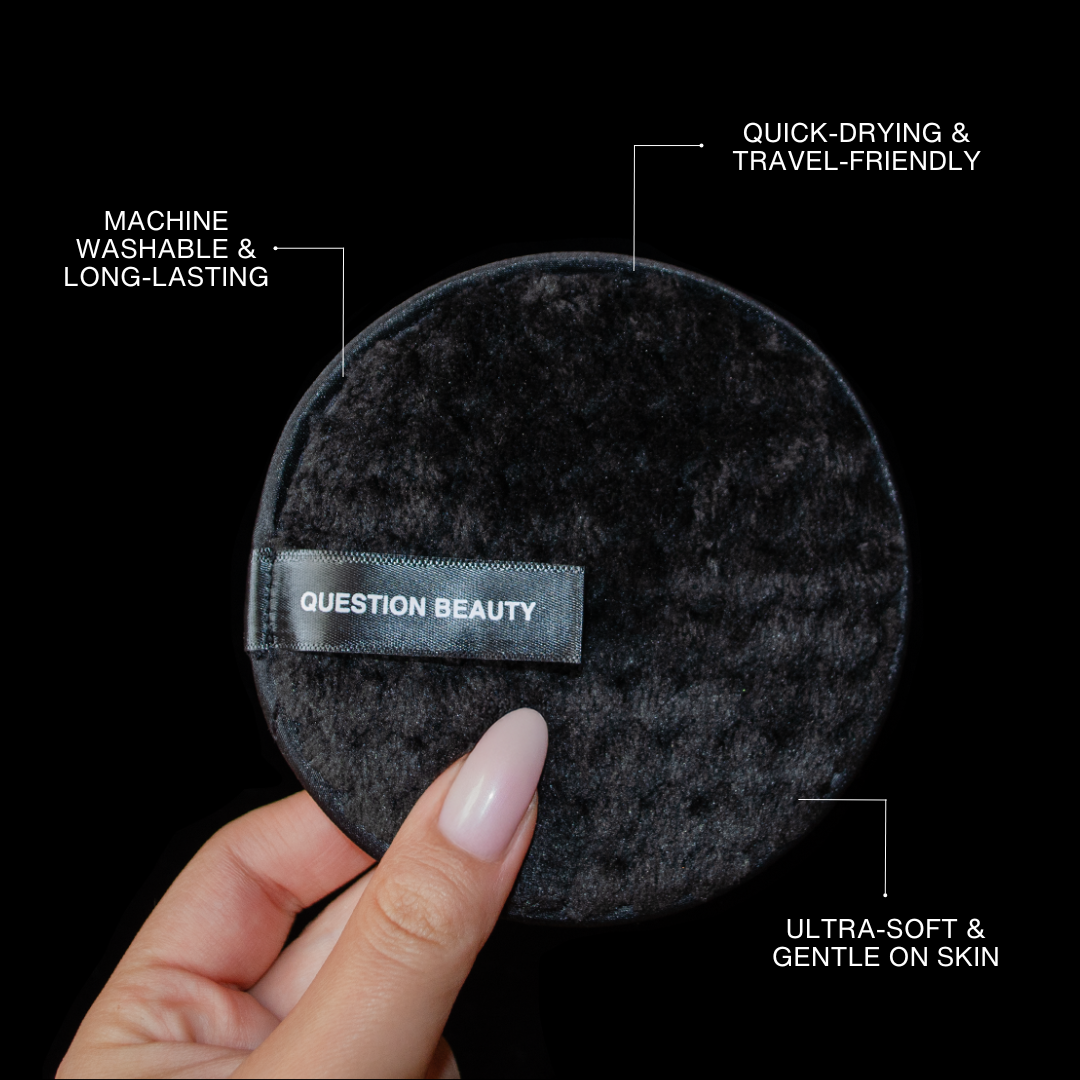 A hand holds a round black cloth against a plain background.