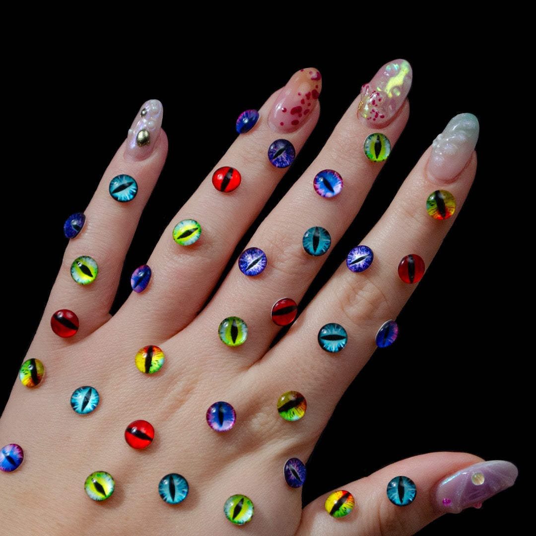 A hand displays colorful, cat eye gems back of the hand against a plain black background.