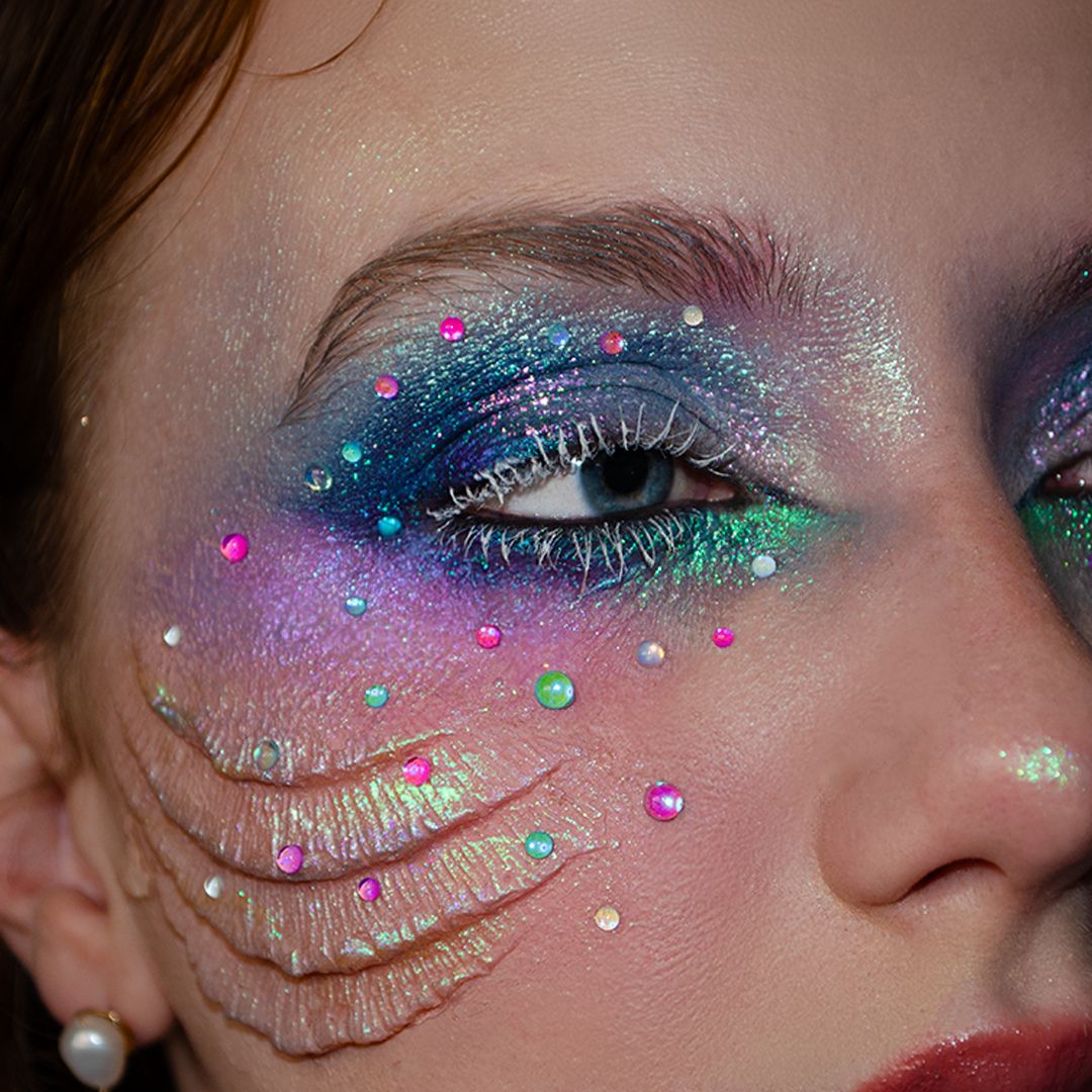 Close-up of an eye decorated with Water Droplet Gems, shimmery blue makeup, and small pearls.