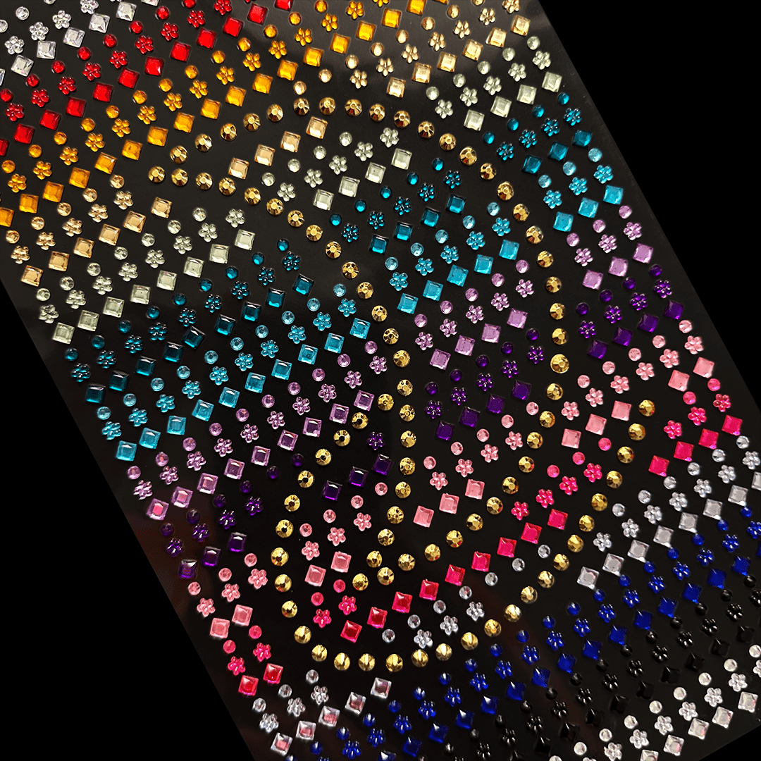 Colorful adhesive gems are arranged in rows and curves on a black sheet.