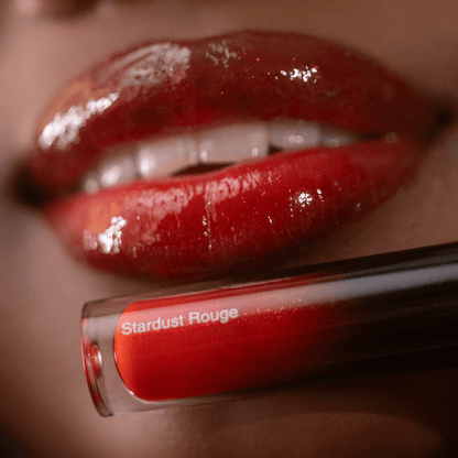 Close-up of glossy red lips with visible text reading Lipgloss Stardust Rouge and a shiny finish near the mouth.
