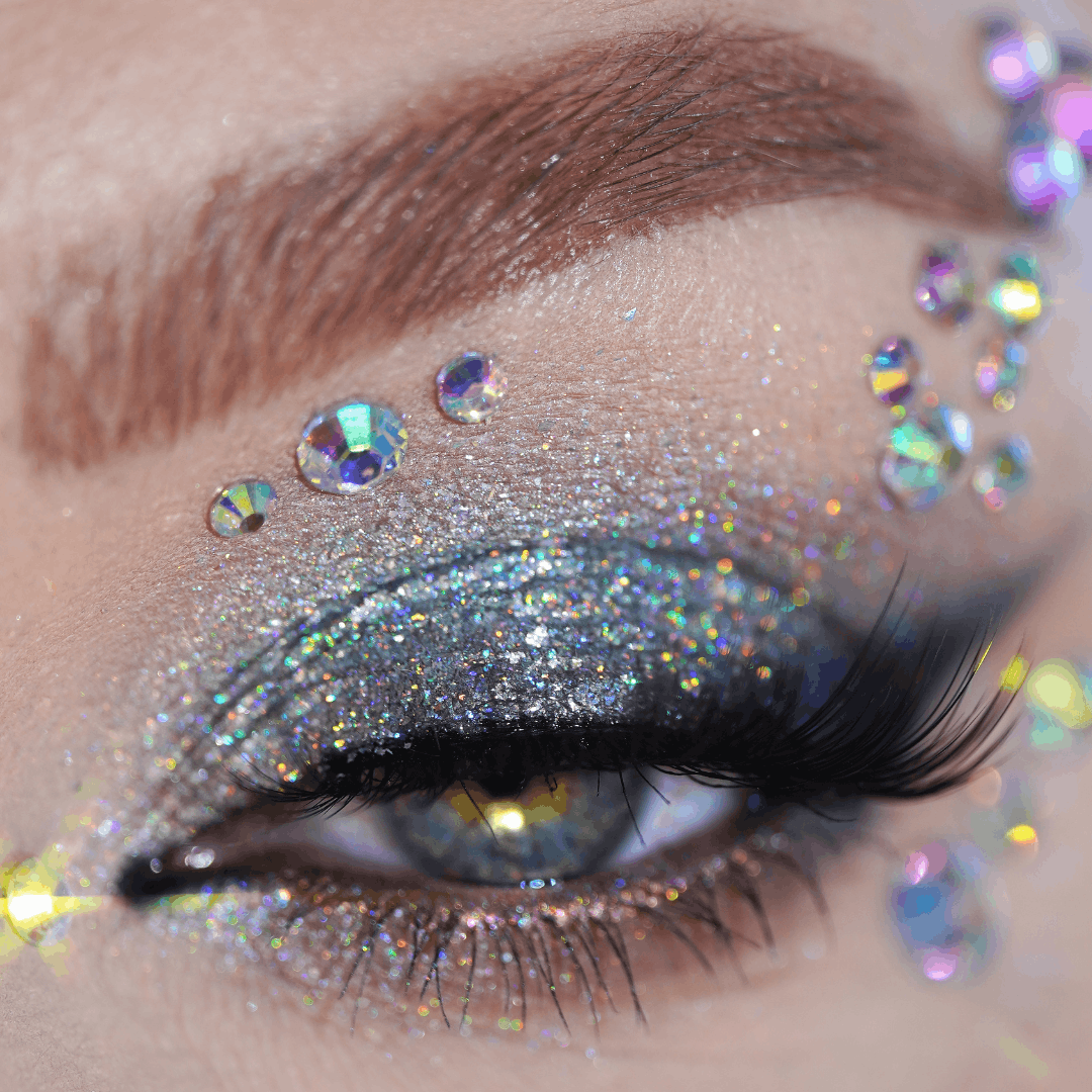 Close-up of an eye with silver glitter eyeshadow, thick lashes, and visible Self-Adhesive Gems around the eyelid.