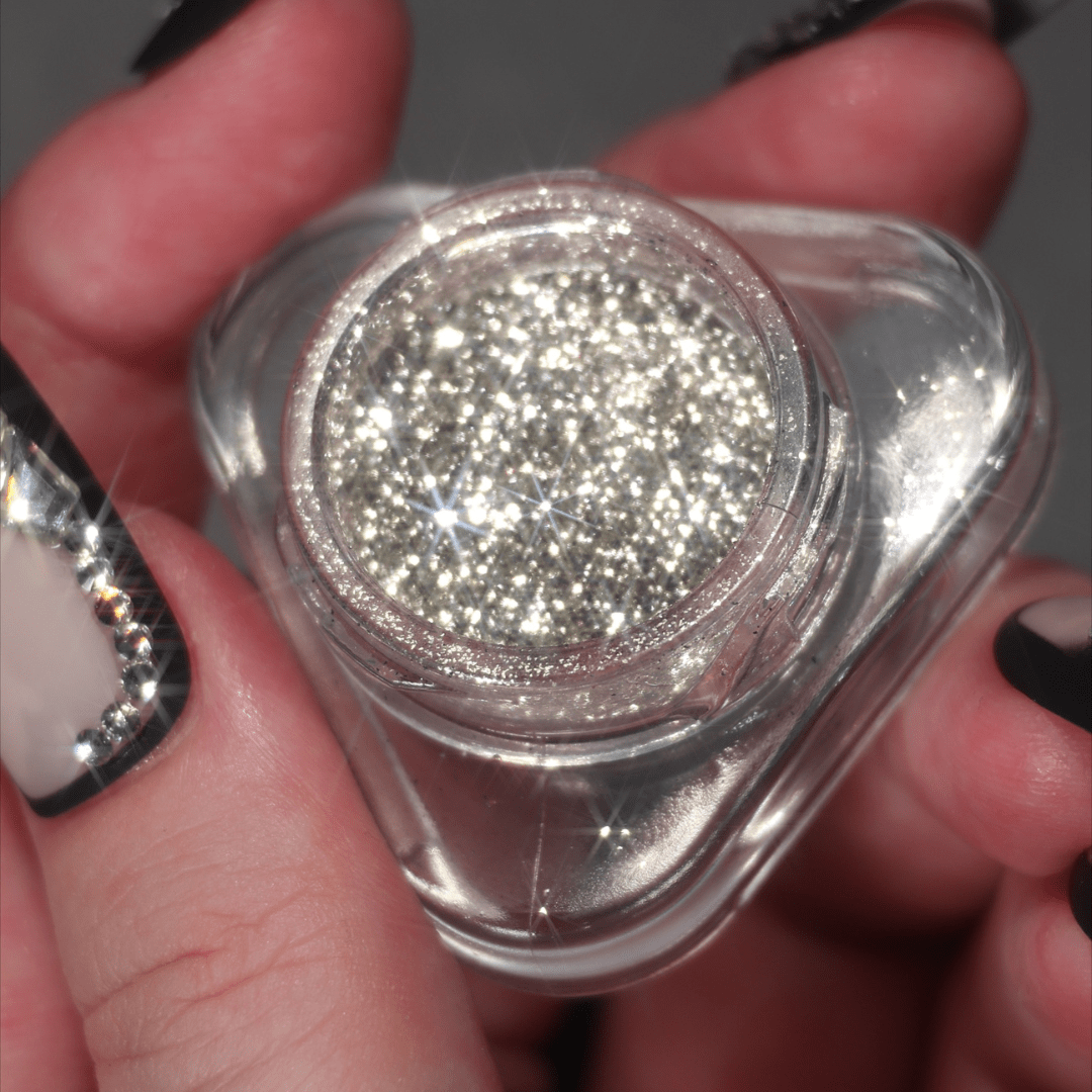 Hands hold a small jar containing sparkling silver glitter.