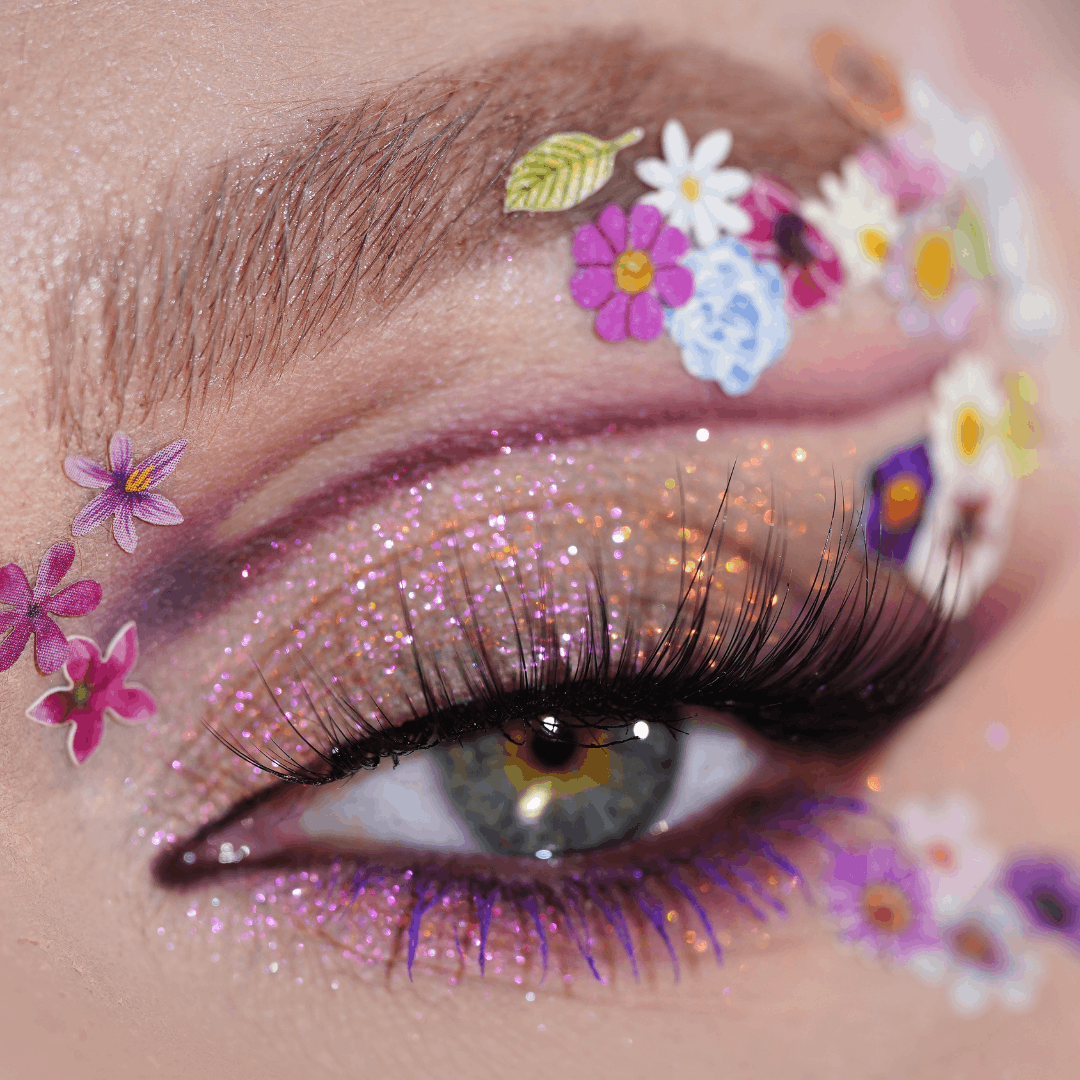 Close-up of an eye with glittery purple eyeshadow and flower stickers; the Creative Mix product is visible.