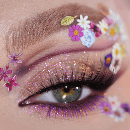 Close-up of an eye with glittery purple eyeshadow and flower stickers; the Creative Mix product is visible.