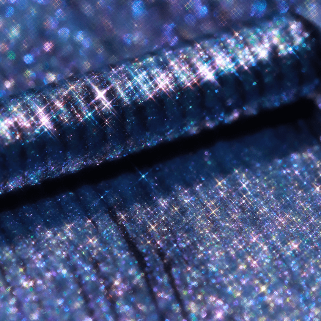 Close-up of a frosty lilac applicator with blue glittery shimmer and light reflections.