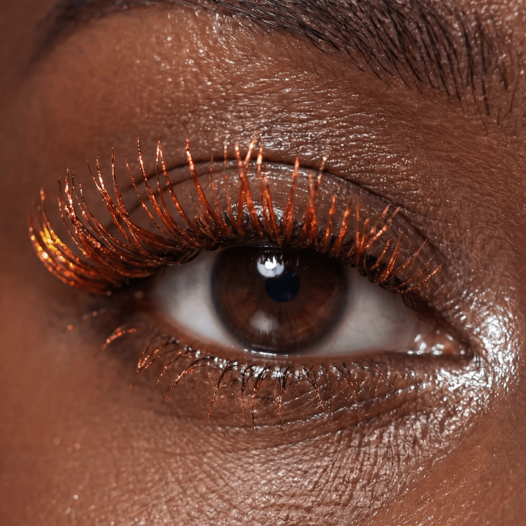 Close-up of a brown eye with orange brown mascara on the lashes