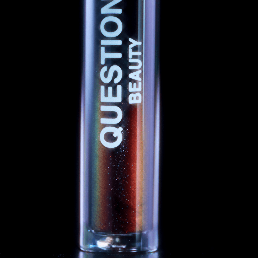 A close-up of a dark mascara topper with a shimmery texture set against a black background.
