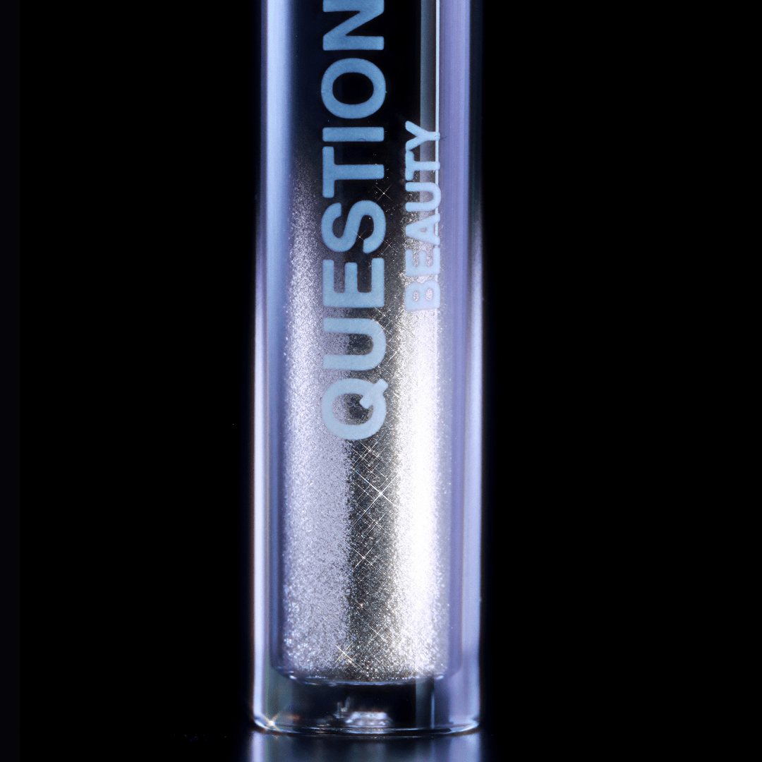 A silver mascara topper labeled Question Beauty rests against a plain black background.