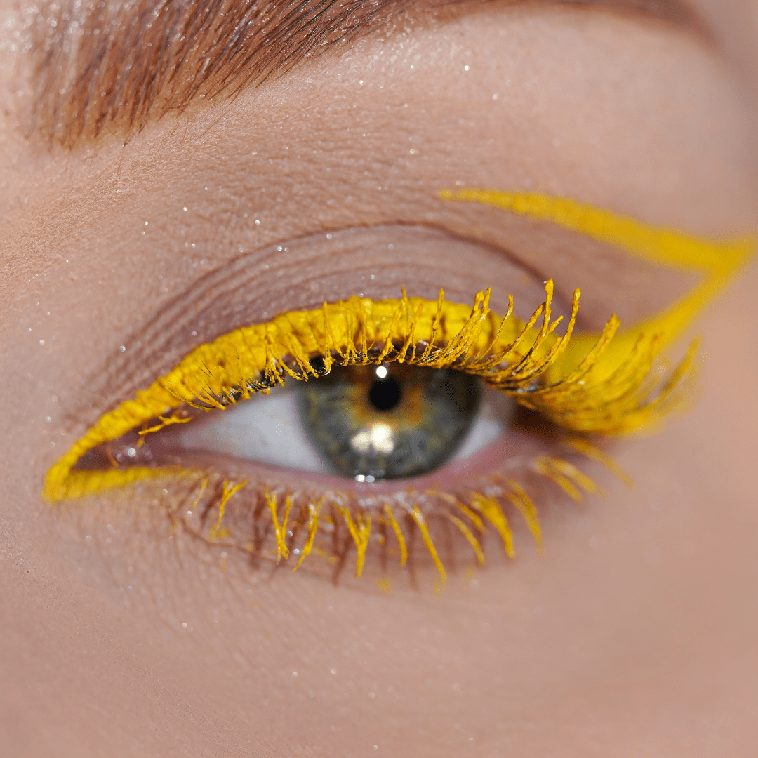 Close-up of an eye with bold yellow eyeliner and black mascara on the lashes