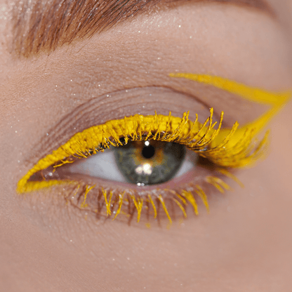 Close-up of an eye with bold yellow eyeliner and black mascara on the lashes