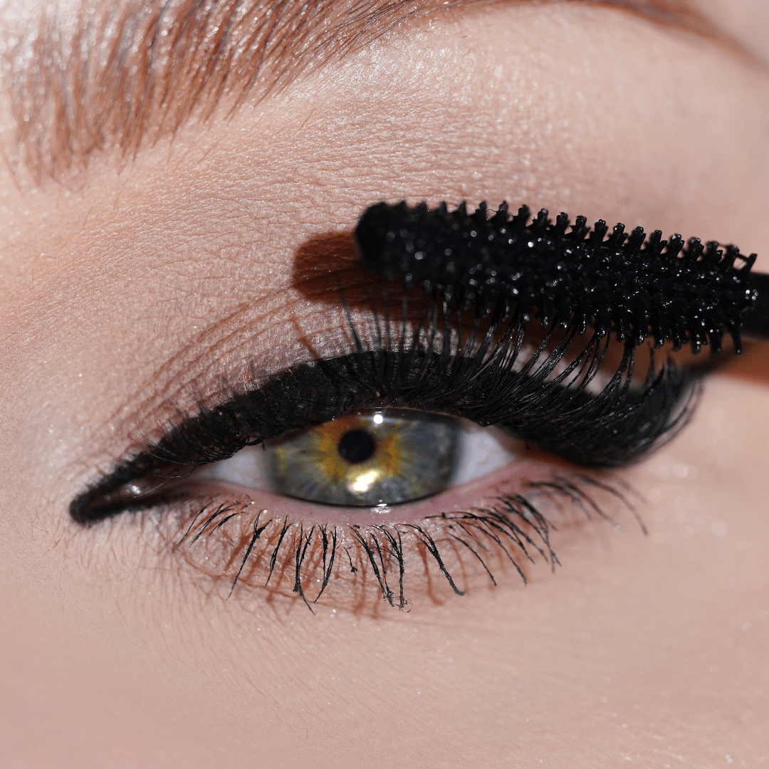 Close-up of an eye with black mascara being applied to the upper lashes.