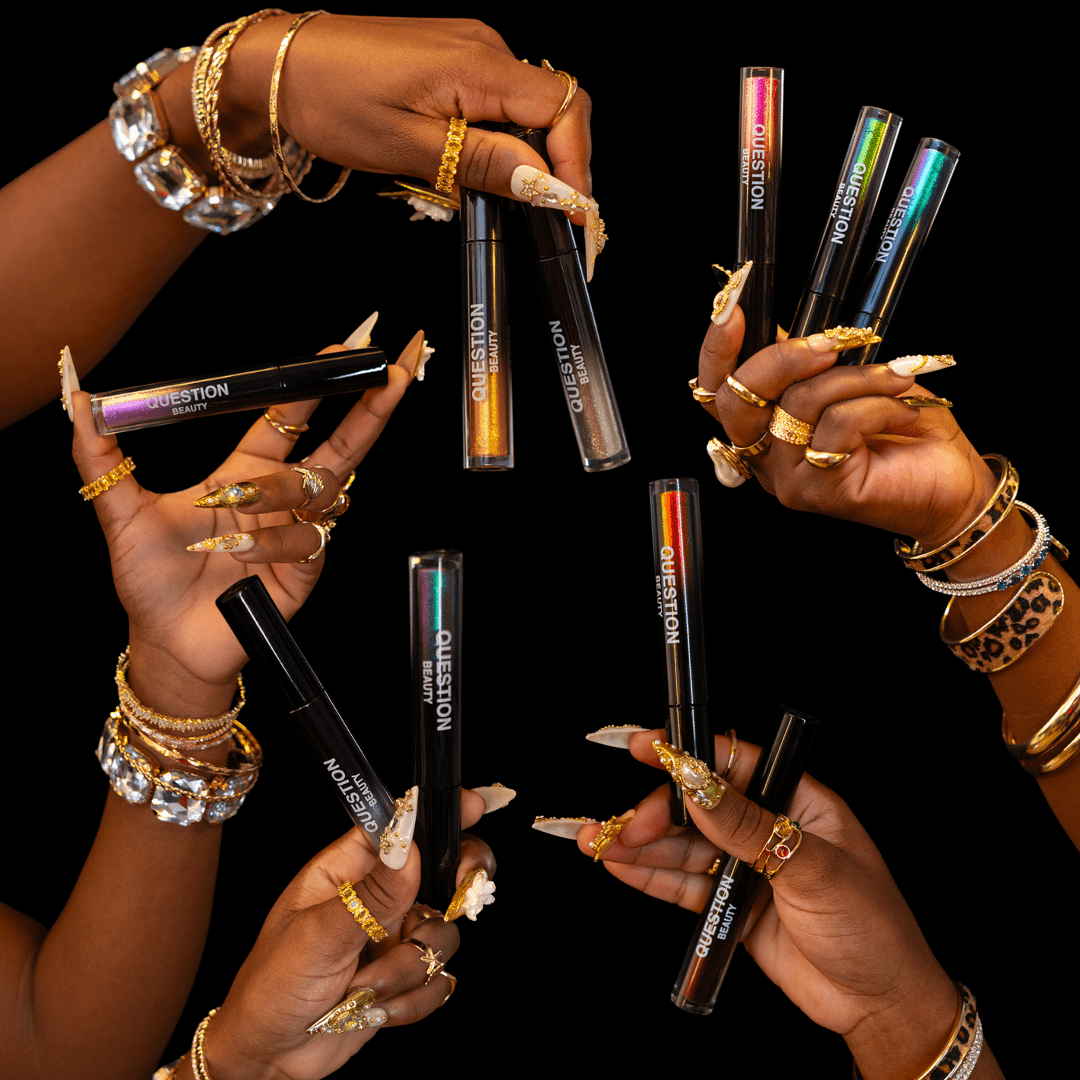 Five hands with jewelry hold colorful mascara tubes labeled Question Beauty against a black background.