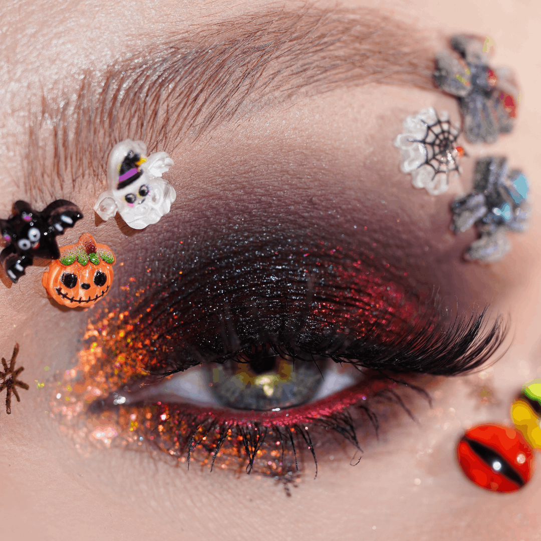 Close-up of an eye with eyeshadow and visible ghost, spiderweb, spider, bat, and pumpkin.gems