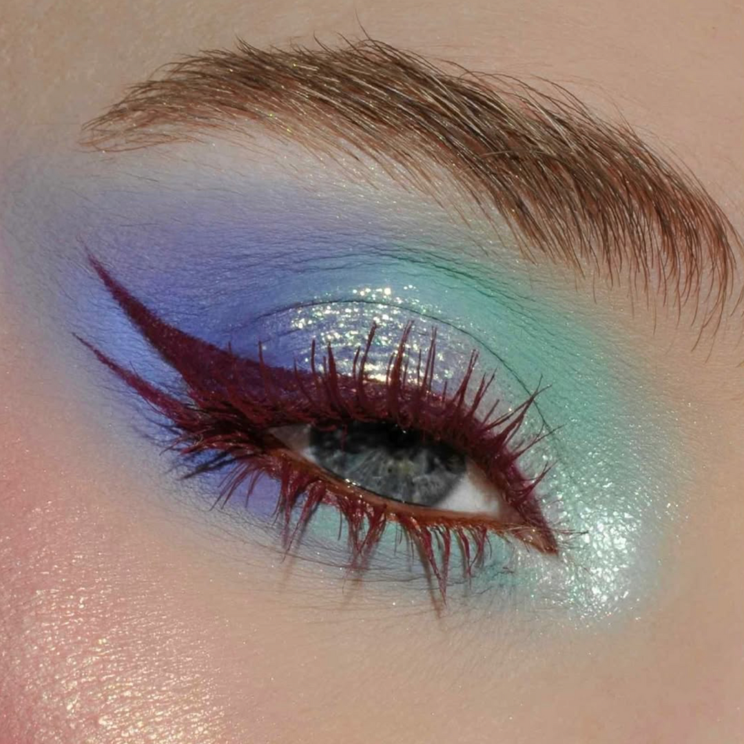 Close-up of an eye with maroon winged eyeliner and blue-mint eyeshadow, mascara applied