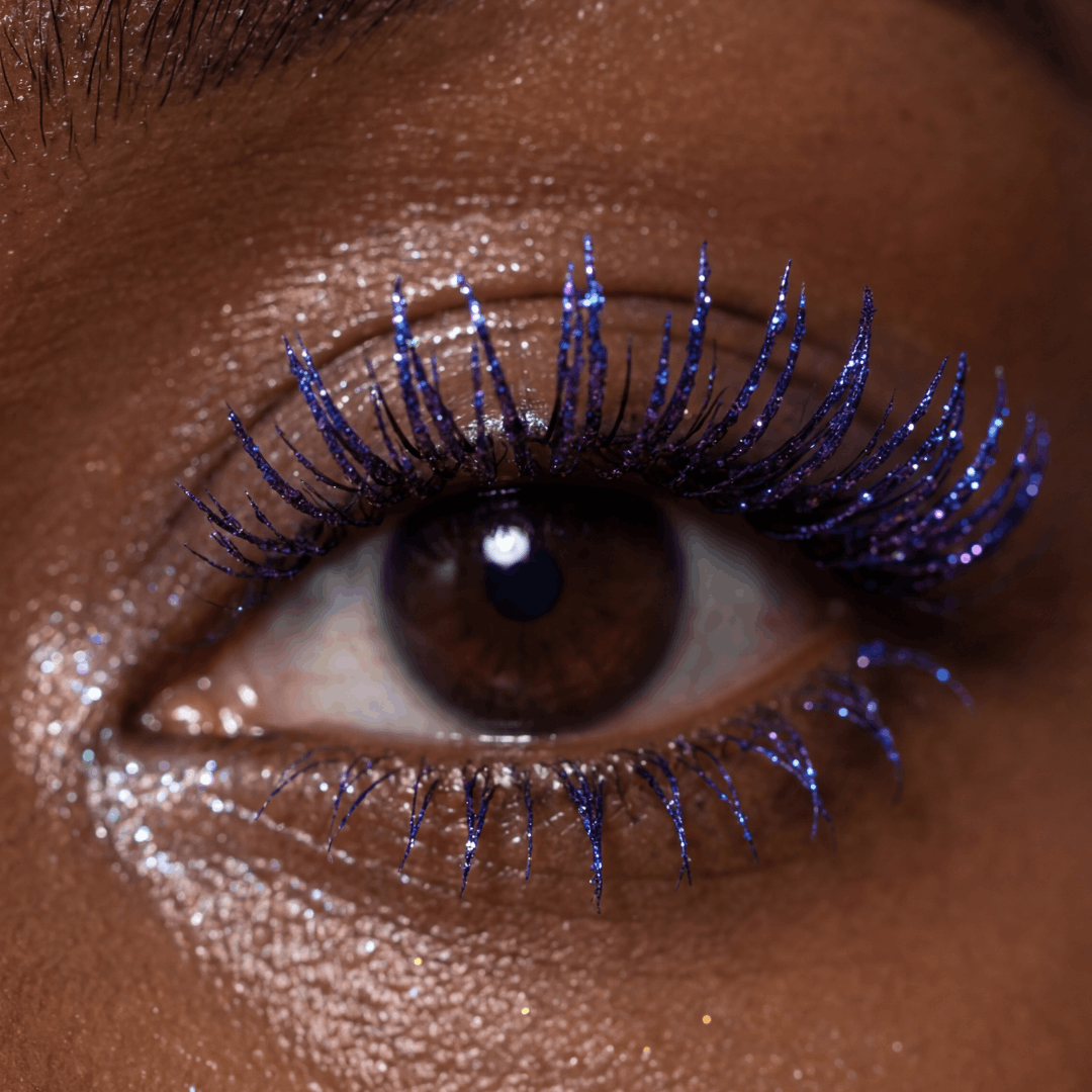 Close-up of an eye with curled lashes coated in shimmery purple mascara