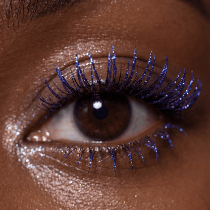 Close-up of an eye with curled lashes coated in shimmery purple mascara