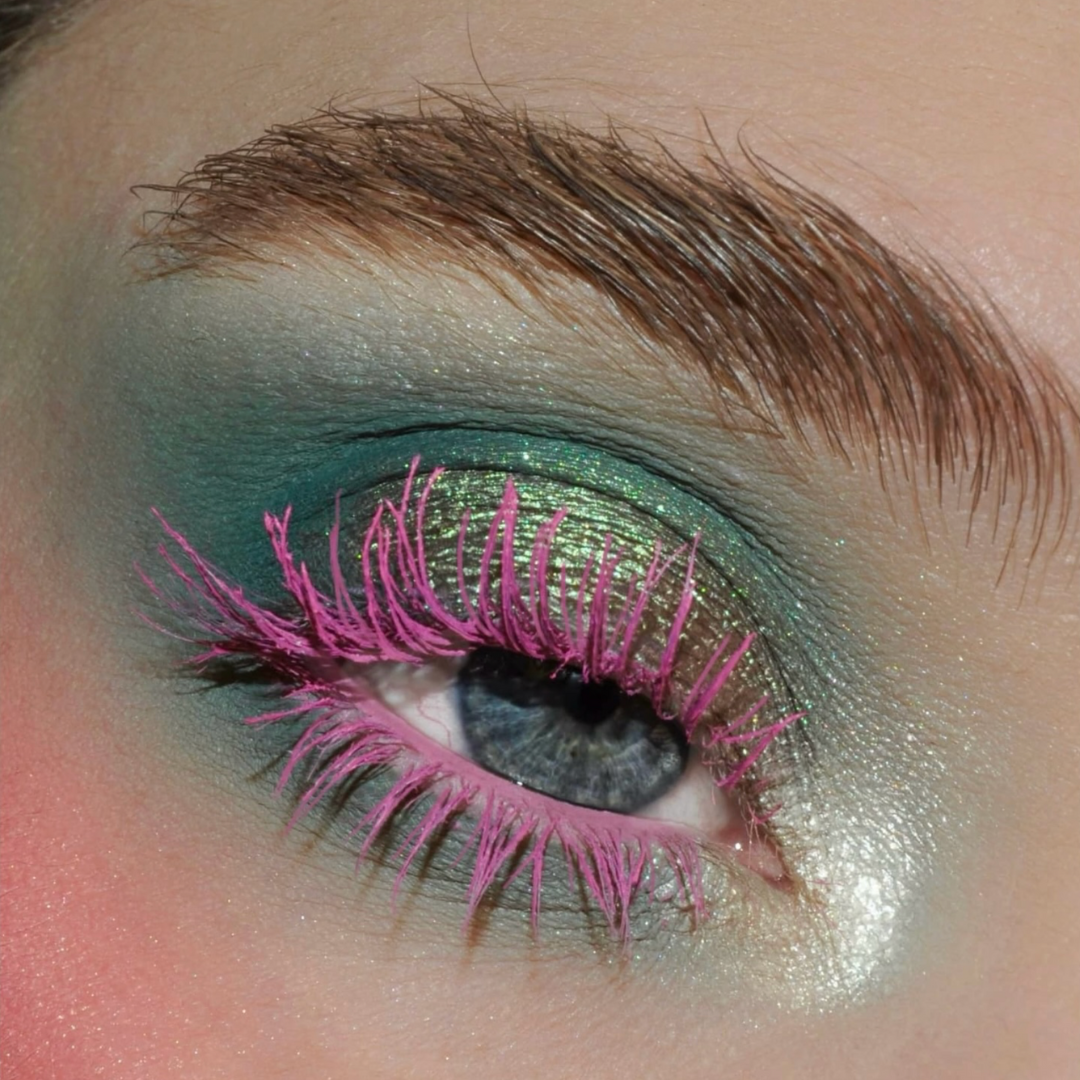 Close-up of an eye with green shimmer eyeshadow and pink lashes.