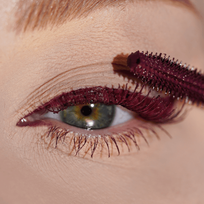 Close-up of green eyes with dark red mascara applied to the upper lashes