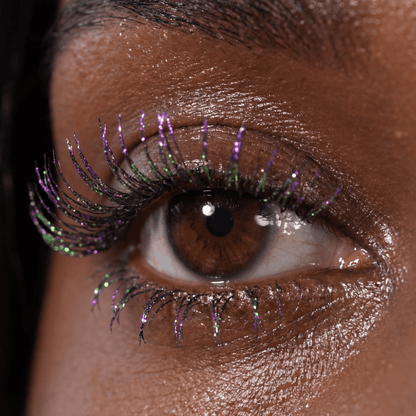 Close-up of a brown eye with visible purple and green shimmer on the lashes