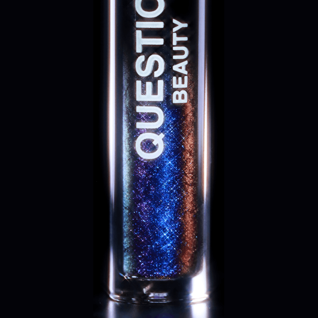 A mascara topper labeled Question Beauty is shown with blue, purple, and copper shimmer on a black background.