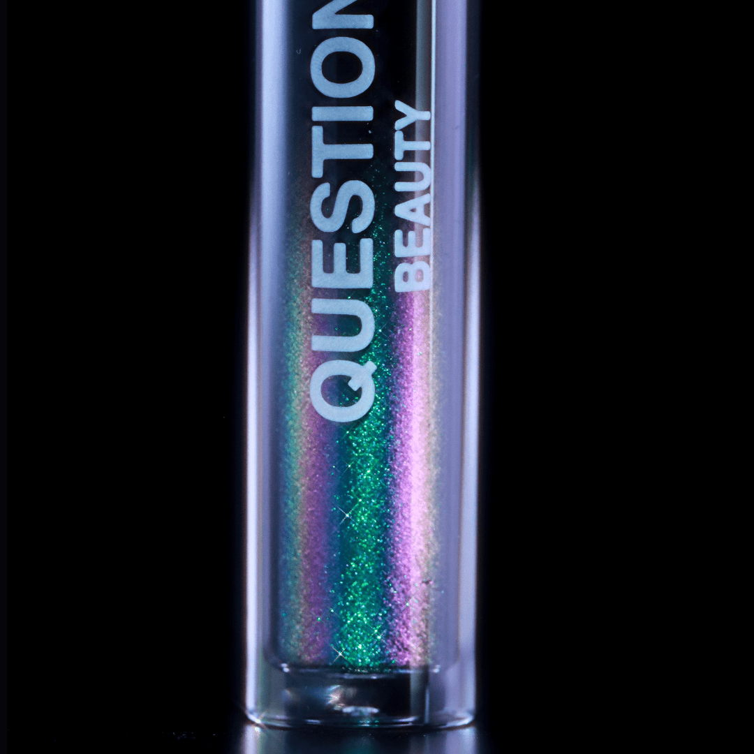 Close-up of a mascara topper tube showing shimmering green and purple gloss against a black background.