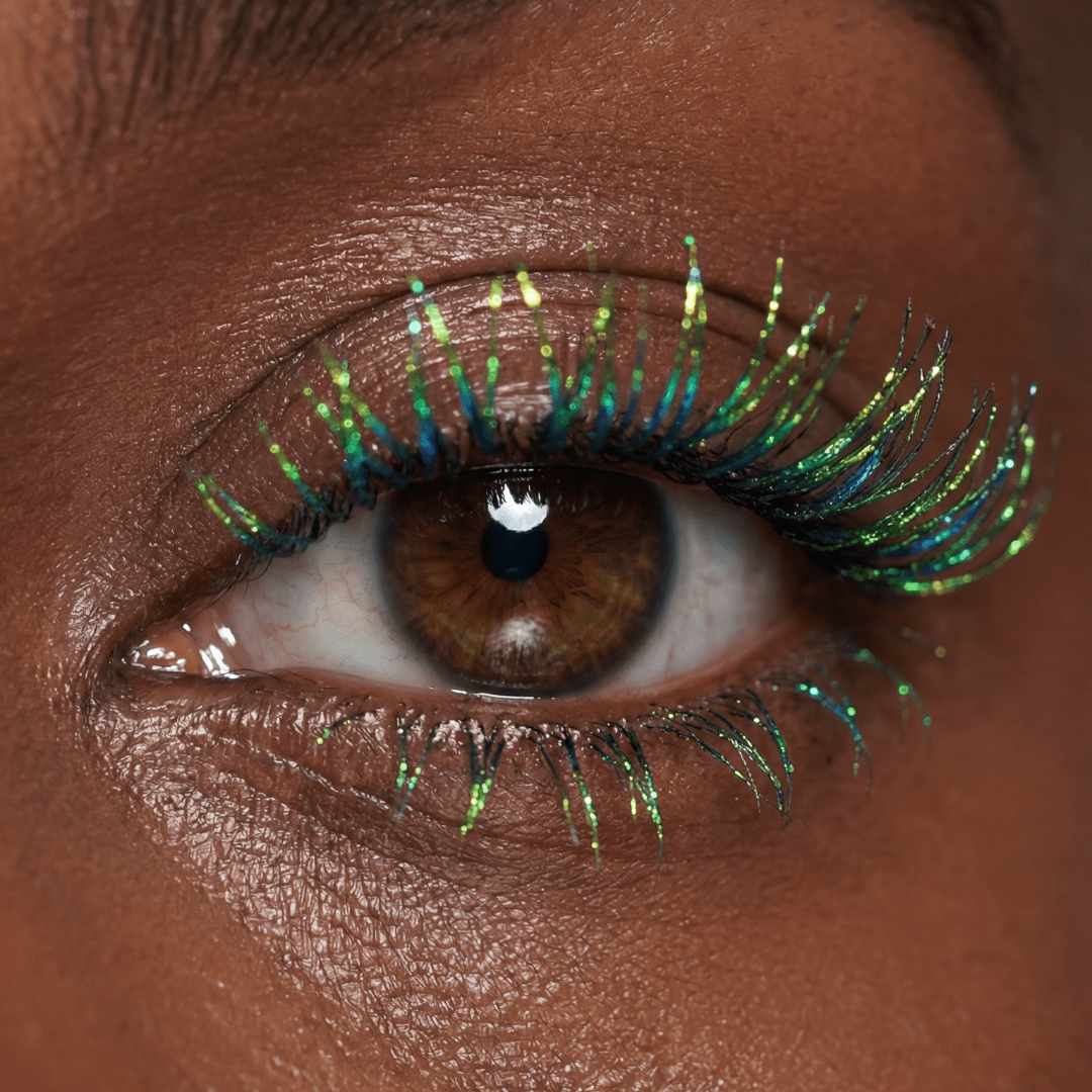 Close-up of a brown eye with blue and green mascara on the lashes