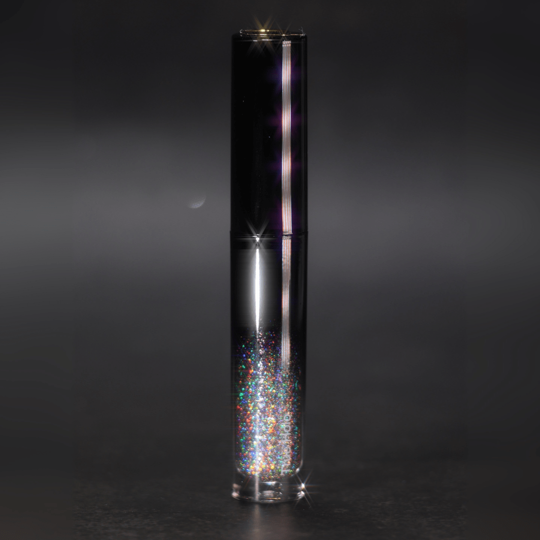 A tube of lip gloss labeled True Holo is upright against a dark blurred background
