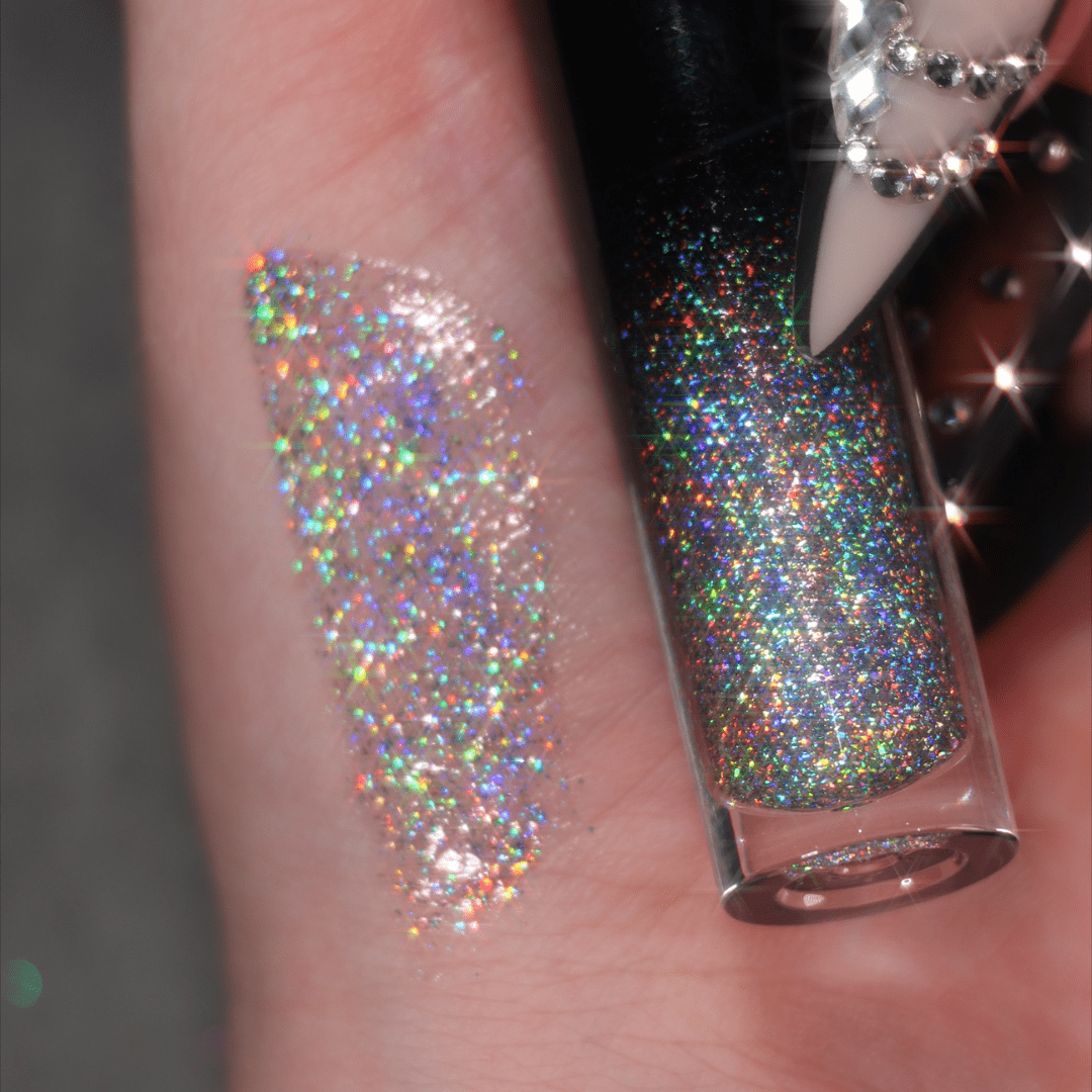 A hand swatch and a lip gloss featuring rainbow holographic glitter are shown on a neutral background.