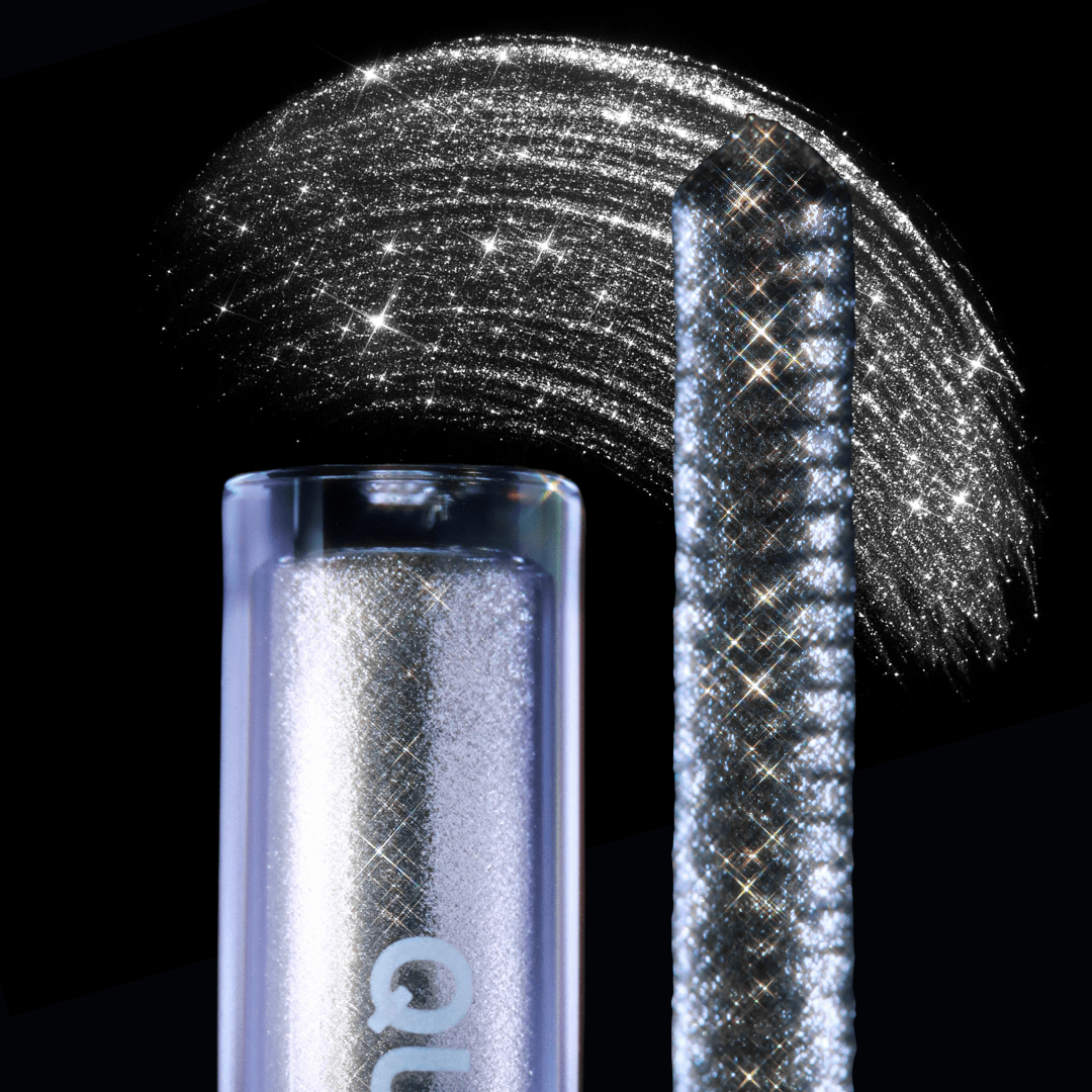 Close-up of a mascara topper and a shimmering silver pigment swatch on a black background.