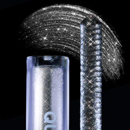 Close-up of a mascara topper and a shimmering silver pigment swatch on a black background.