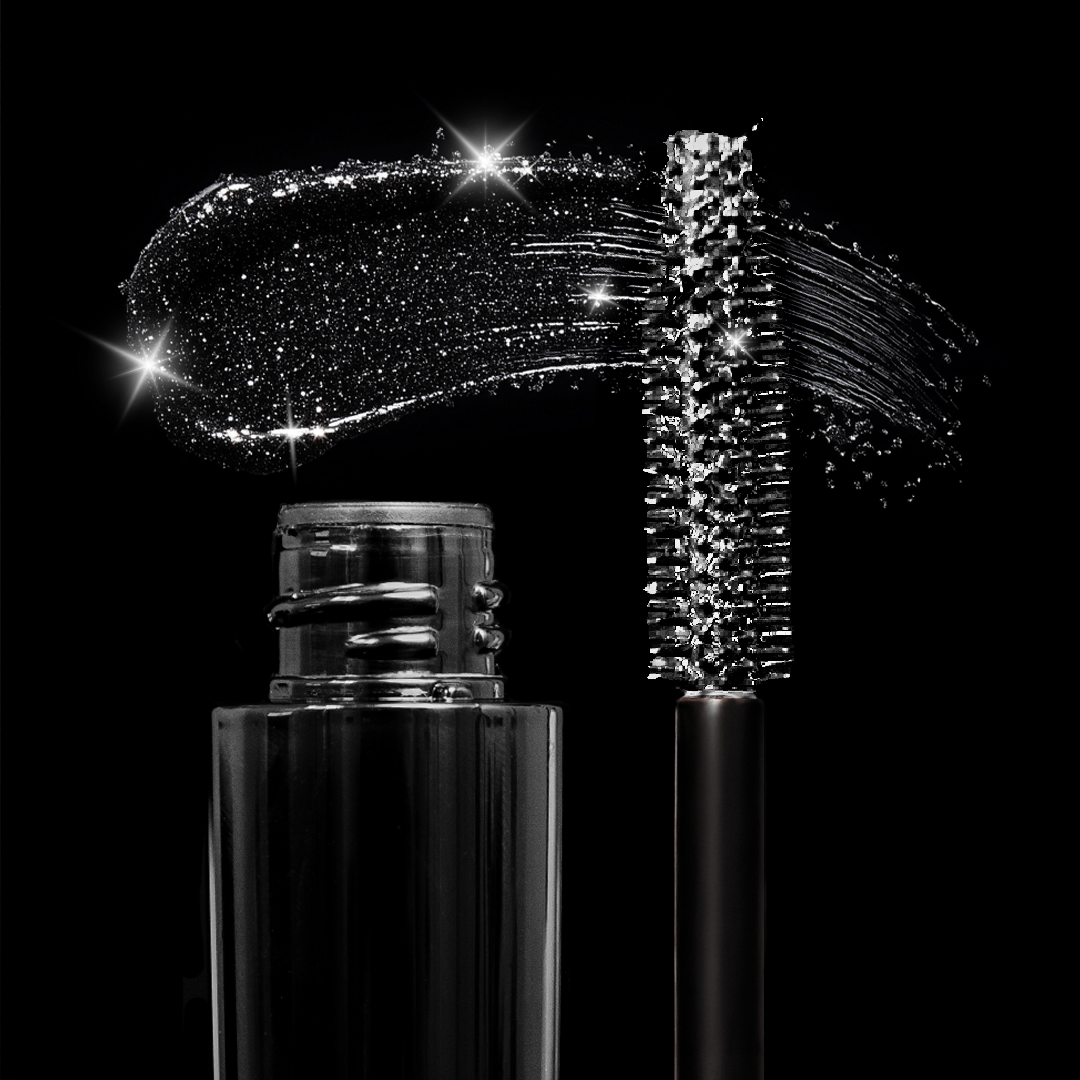 Black mascara wand, sparkly gloss smear, and bottle arranged on a black background with shimmering reflections.