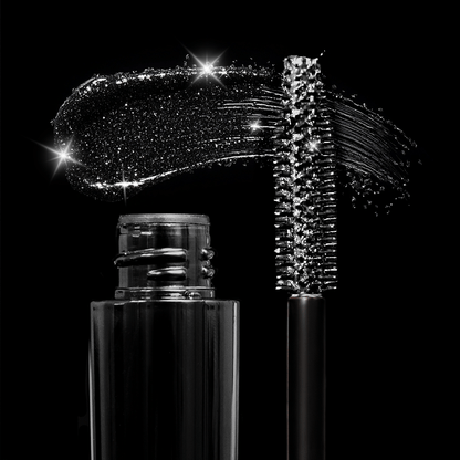 Black mascara wand, sparkly gloss smear, and bottle arranged on a black background with shimmering reflections.