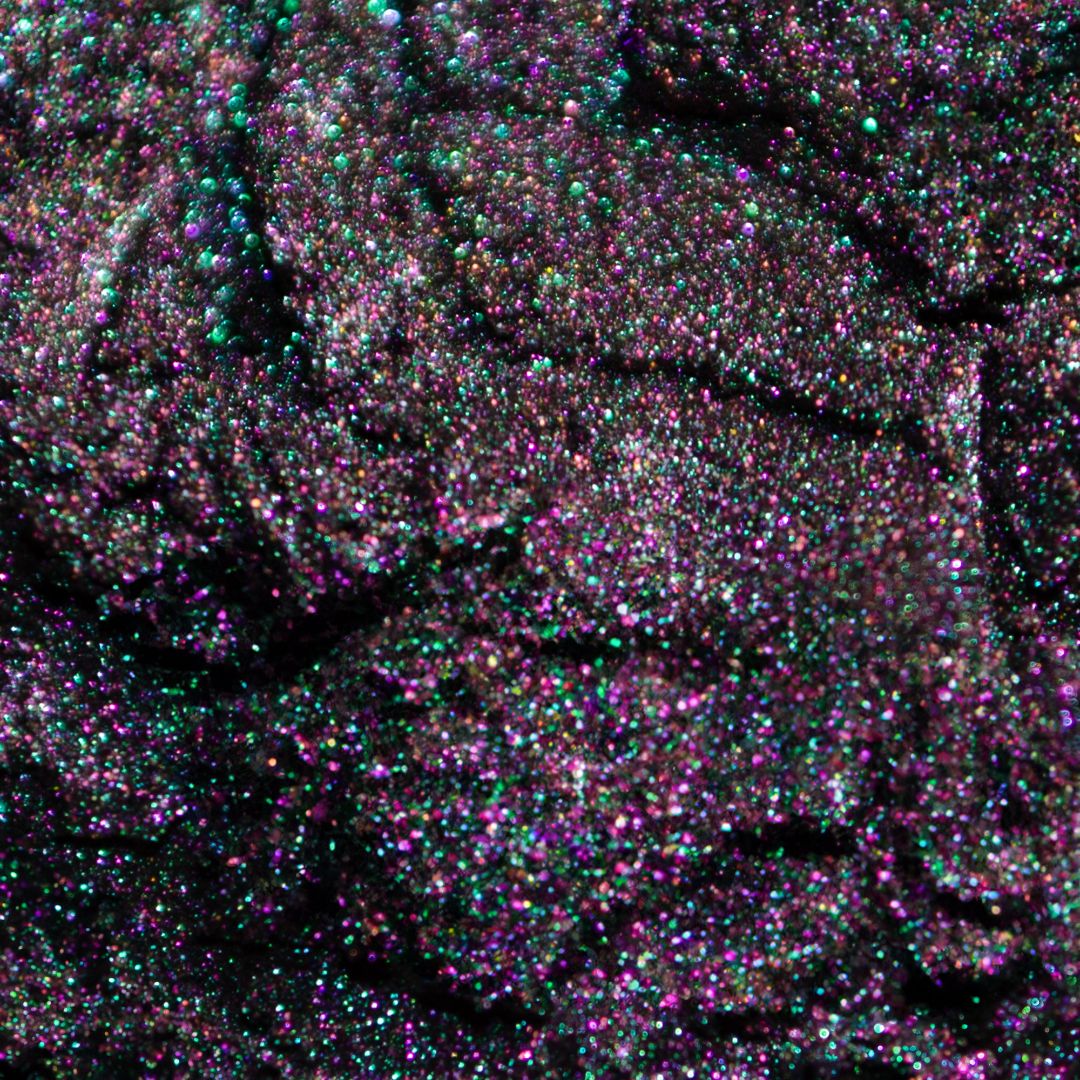 Close-up of shimmering holographic glitter with visible purple, green, and blue specks.