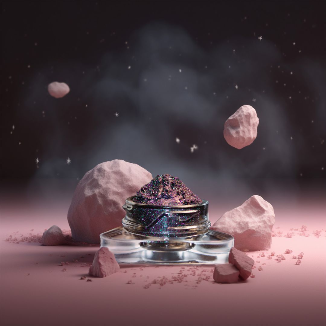 A small clear jar filled with holographic dark grey  pigment sits on a pink surface with pink rocks and dust under a starry sky.