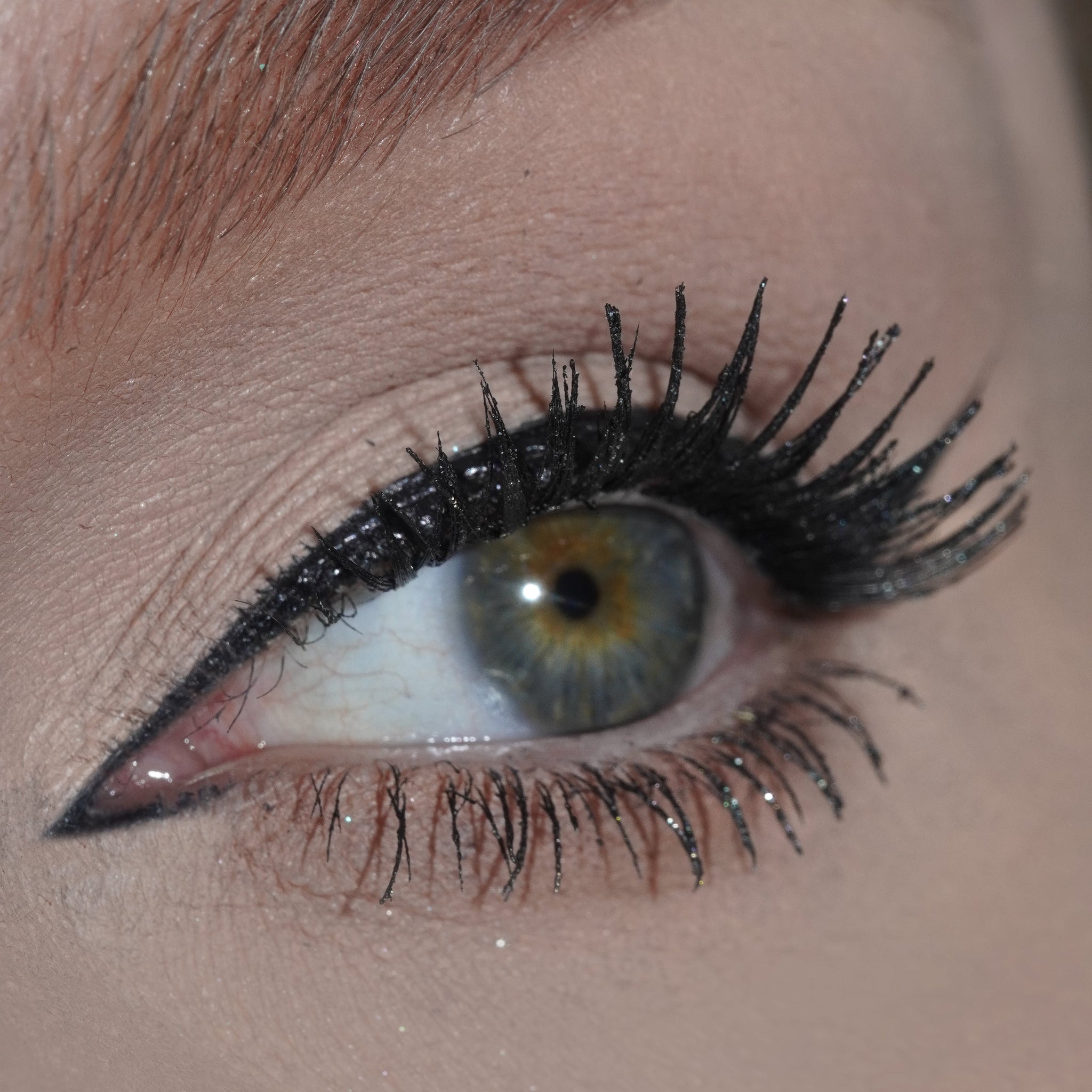 Close-up of a greenish-hazel eye with bold black winged eyeliner and long lashes.