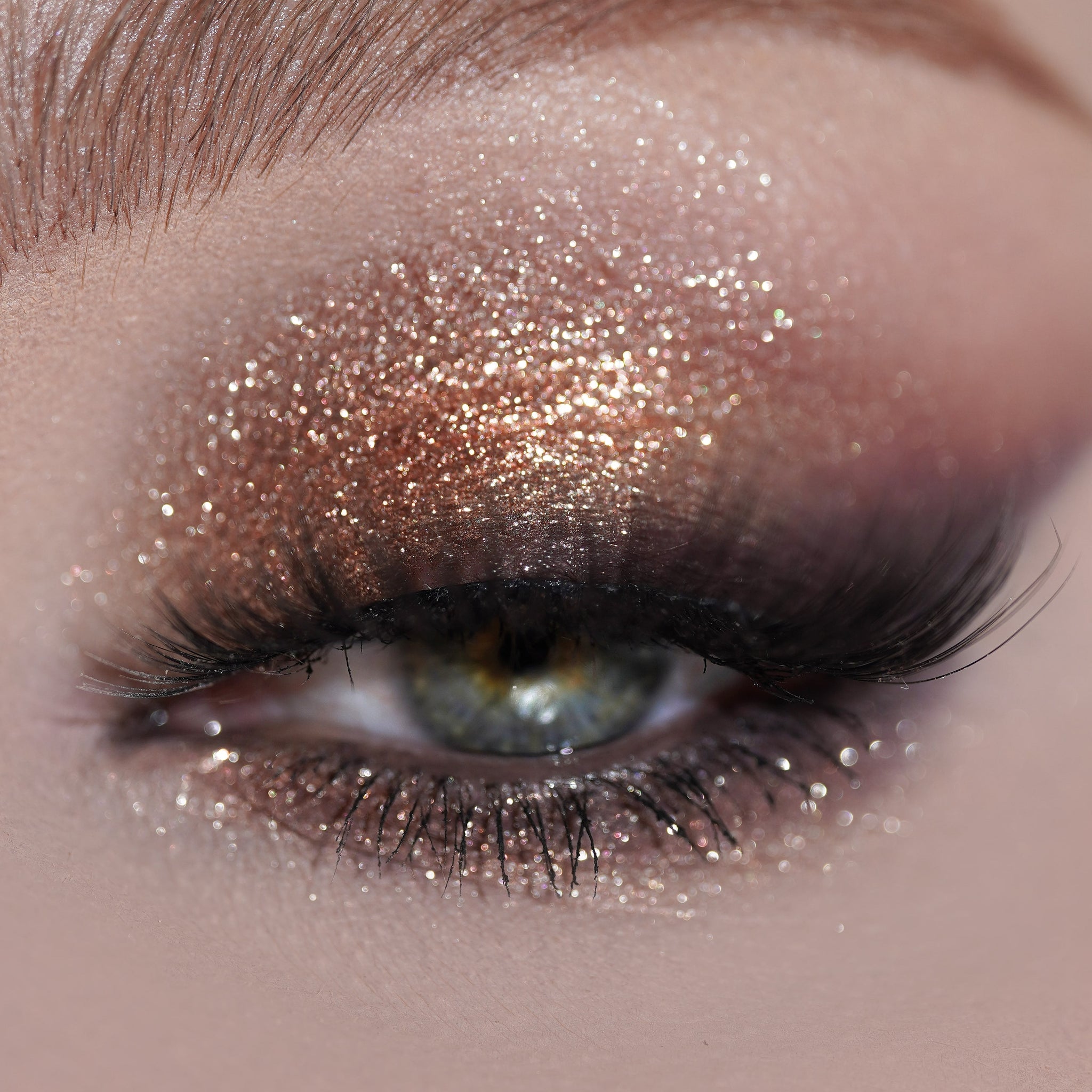 Close-up of an eye with shimmery golden-rose eyeshadow and long dark eyelashes