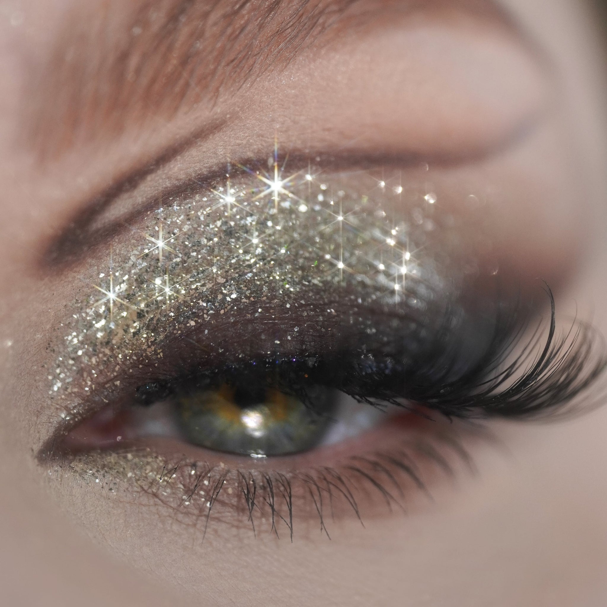 Eyelids are covered in shimmery silver eyeshadow with a sparkling, reflective effect.
