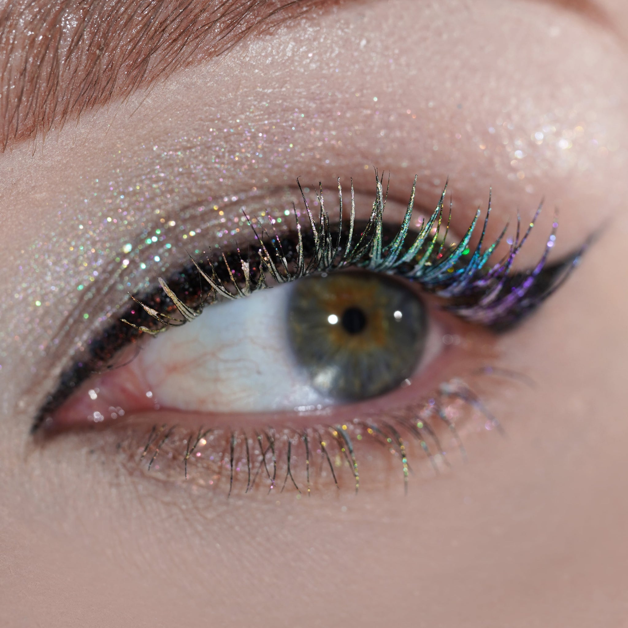 Close-up of an eye with glittery highlighter applied to the eyelid.