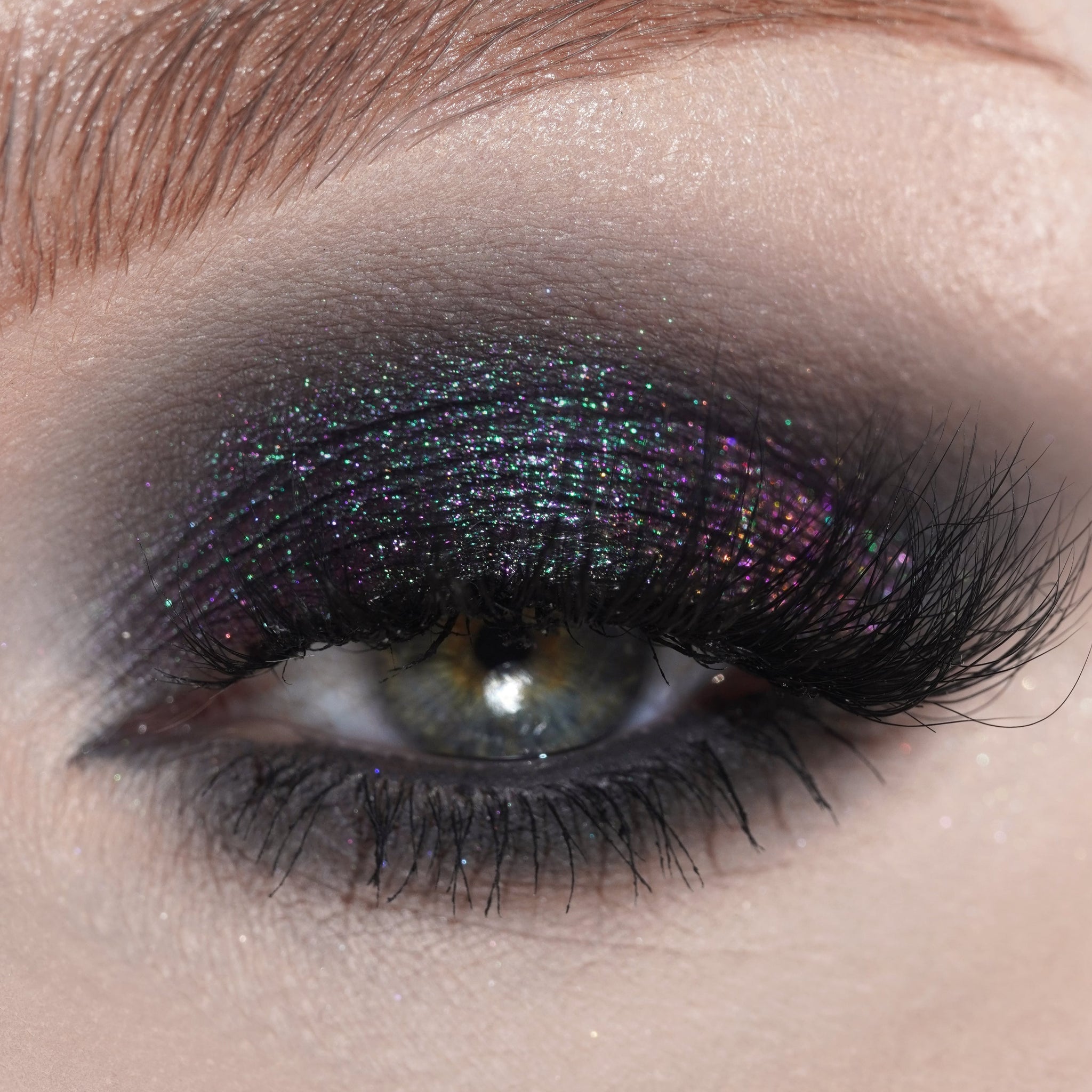 Close-up of an eye with shimmering black eyeshadow and thick, long lashes.