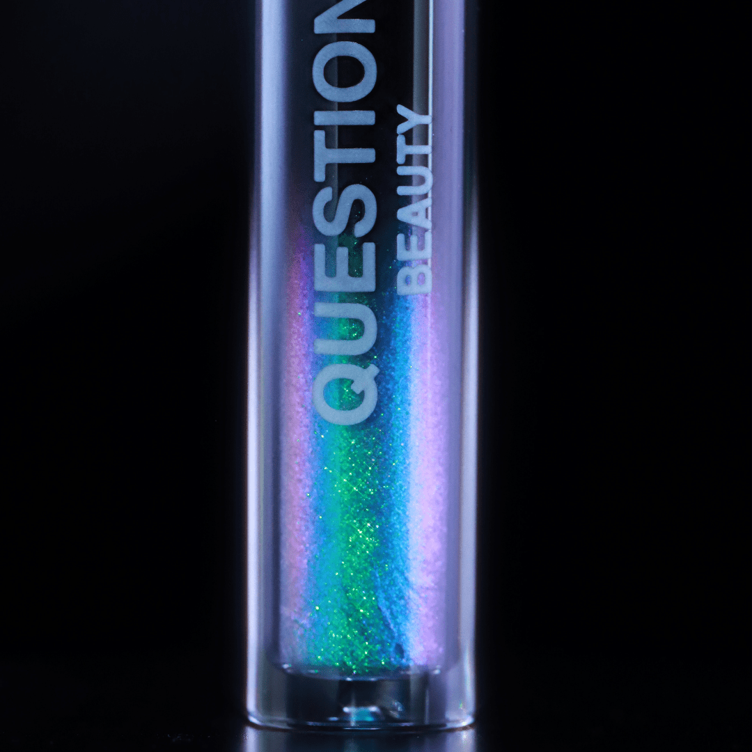 A tube labeled Question Beauty with blue, purple, and green shimmer sits against a black background.