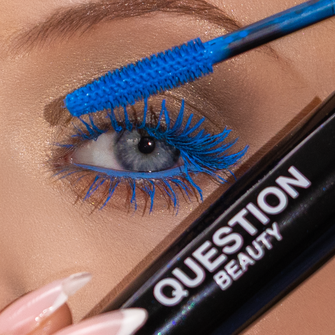Close-up of a person with blue eyes applying mascara to their upper lashes
