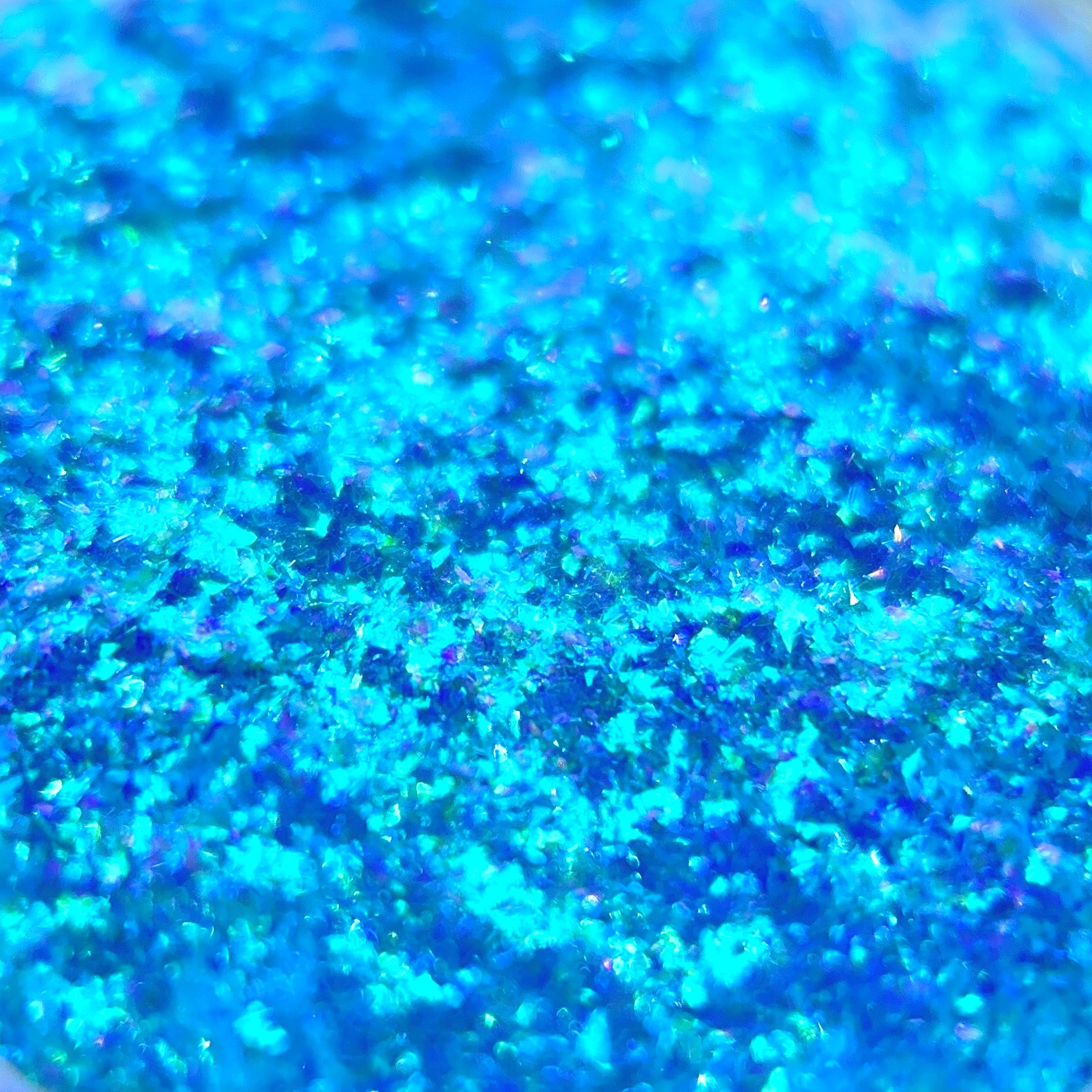 Small blue glitter flakes with iridescent highlights create a textured surface.