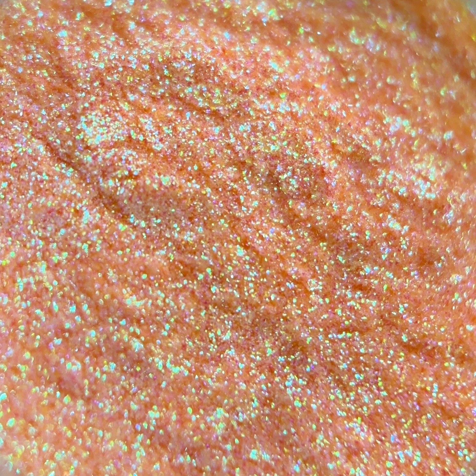 Close-up of an pink-gold glitter with iridescent sparkles and metallic shine.