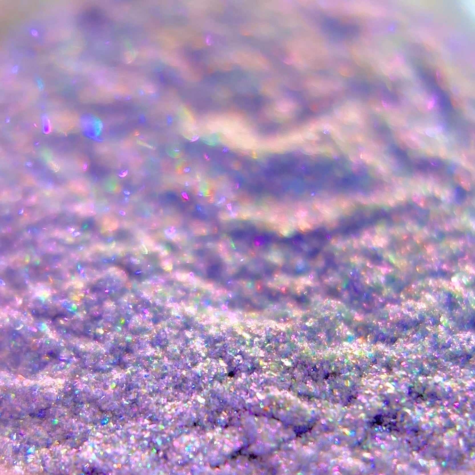 Close-up of iridescent purple glitter with holographic pink and blue highlights.