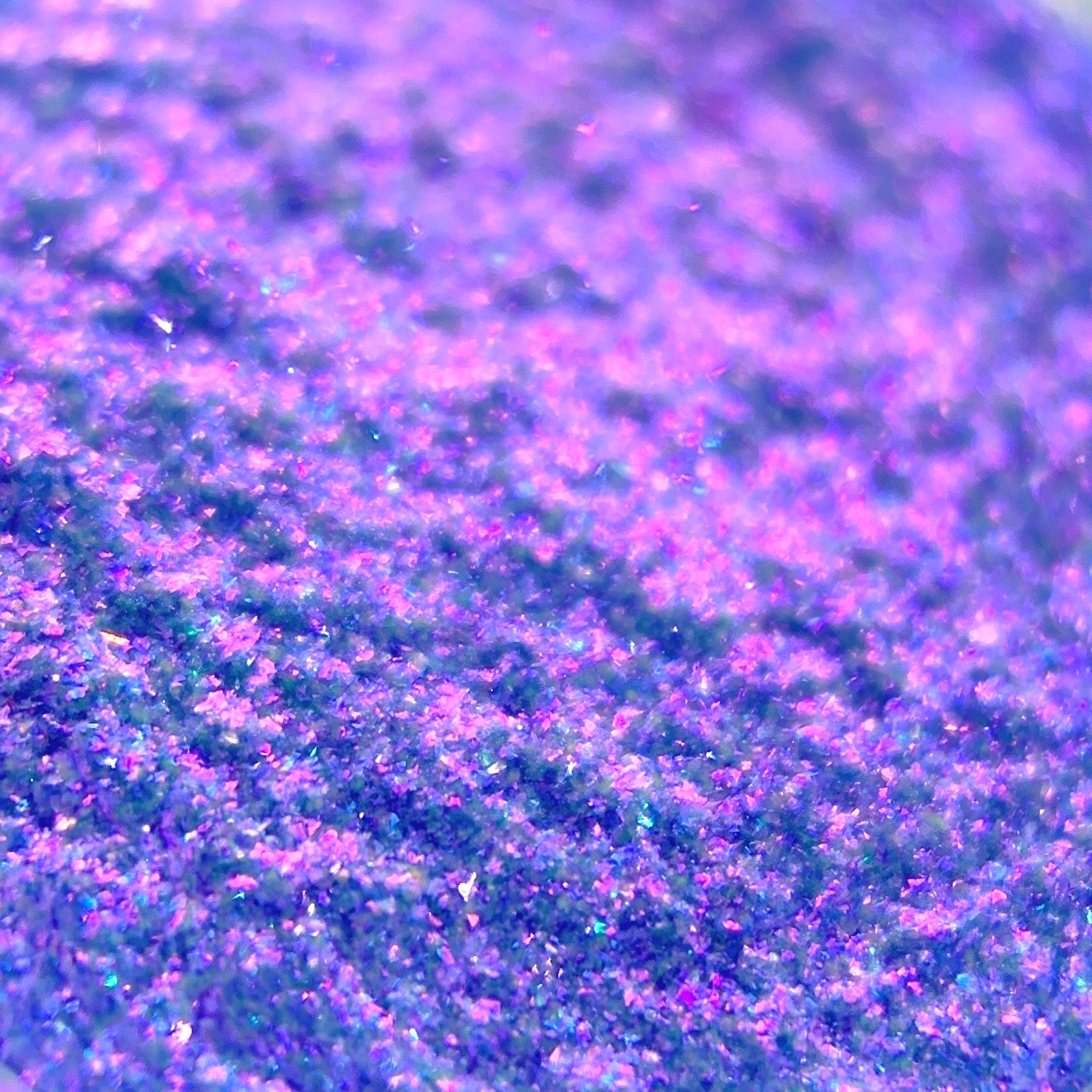Close-up of purple-blue holographic glitter in an abstract pattern with a shimmering texture.