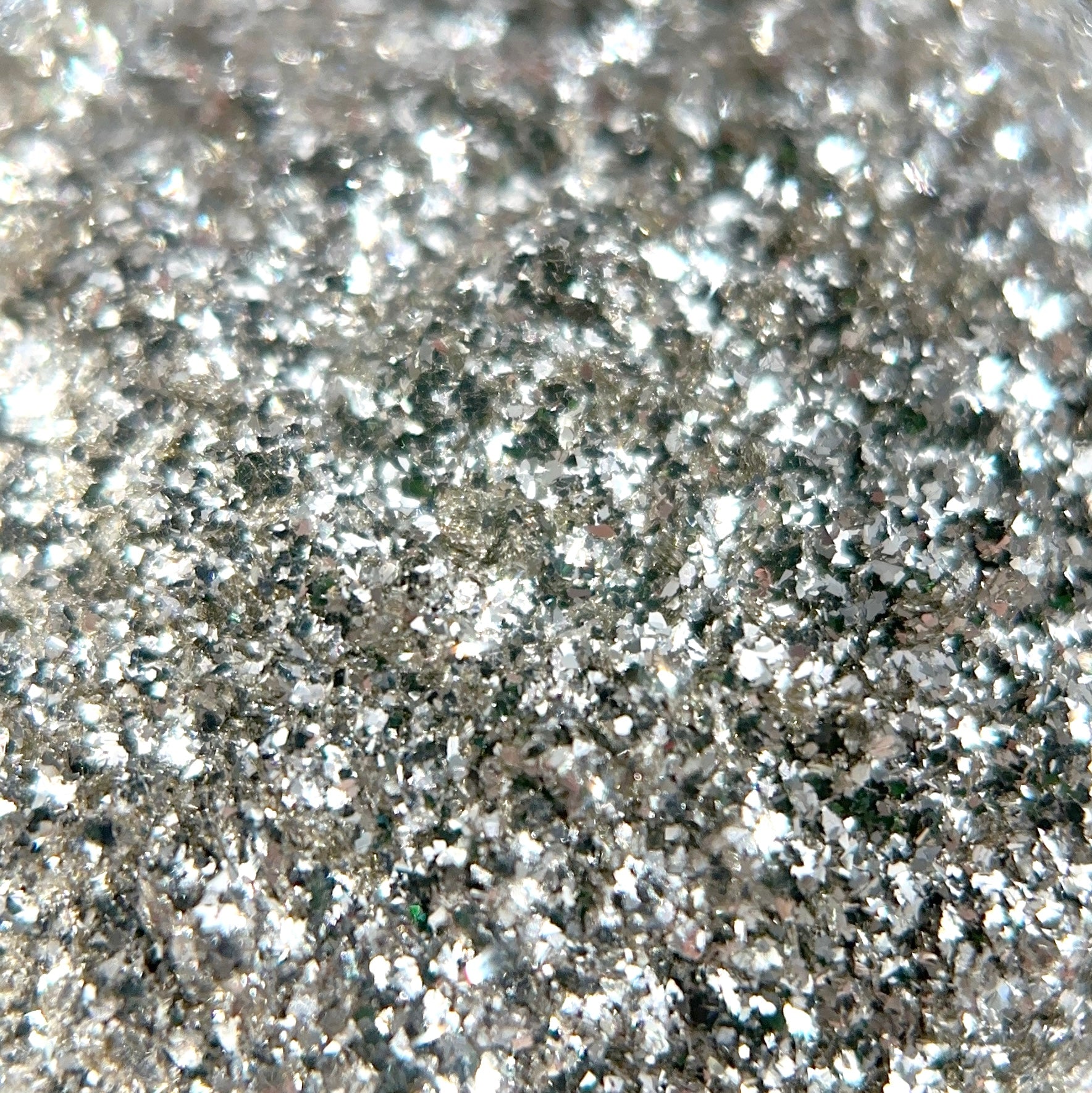Close-up of scattered silver glitter particles creating a textured reflective surface.