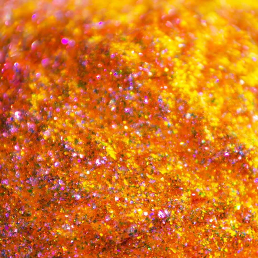 Close-up orange glitter with yellow, pink and gold highlights.