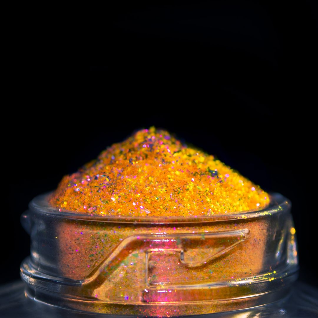 A clear jar of bright yellow glitter and pink accents is shown close up against a black background.