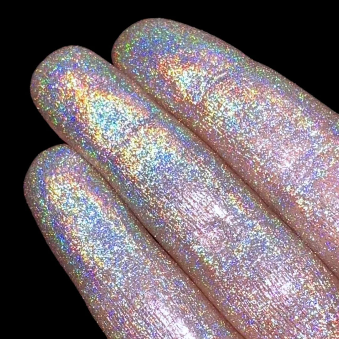 Fingers with holographic glitter are shown against a plain black background.